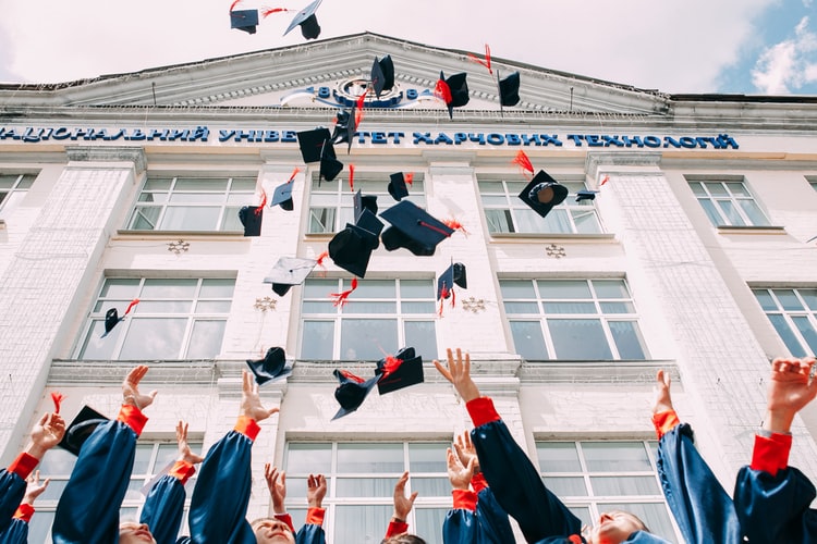 group of nursing school graduates throwing their caps in the air