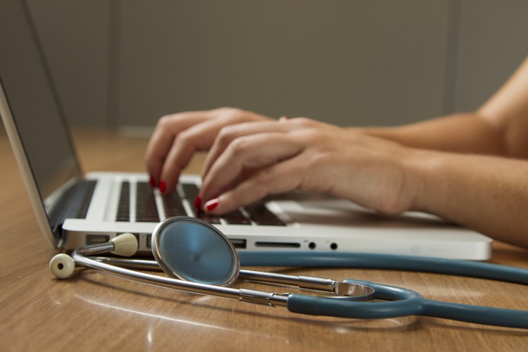 Travel Nurse Typing On Computer With Stethoscope